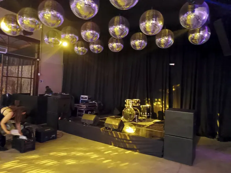 Palco com bateria e caixas de som, sob bolas de espelho